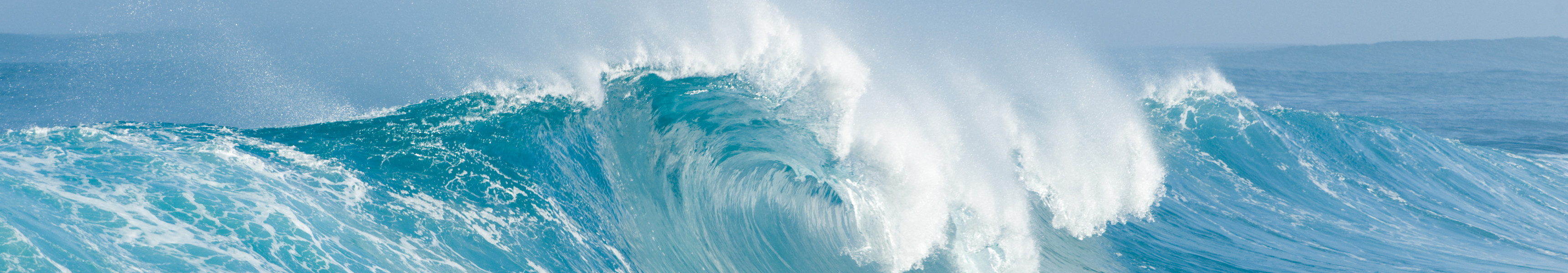 Große Welle bricht im eisblauen Meer